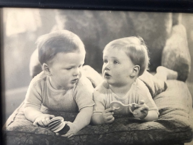 A black and white photo of babies lying on a bed.